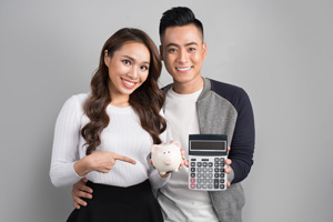 Young Asian Couple holding piggy bank and calculator